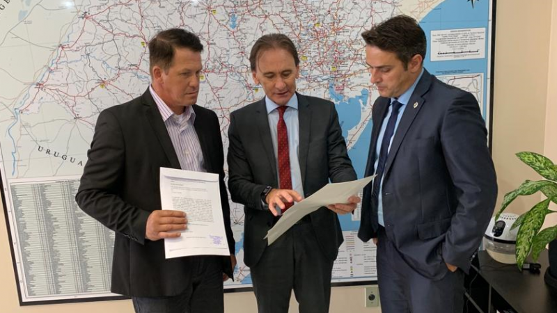 Na foto, o secretário Juvir Costella olha um documento, juntamente com o deputado estadual Tenente-Coronel Zucco e o empresário Sandro Fantinel