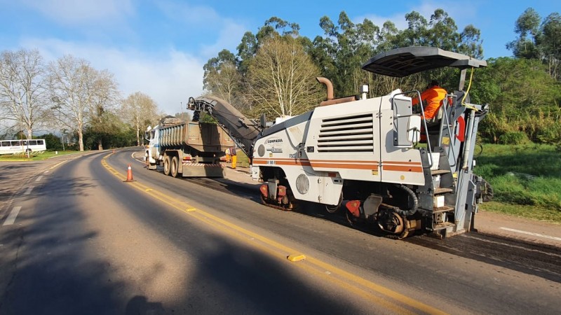 A foto mostra uma máquina de fresagem realizando o recorte do pavimento na rodovia ERS-129, em Muçum, no Vale do Taquari. Na frente do equipamento está um caminhão, que recolhe o material retirado.