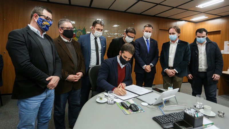 A foto mostra o governador Eduardo Leite, o vice, Ranolfo Vieira Júnior, e secretários estaduais durante o ato de assinatura do edital da RSC-287