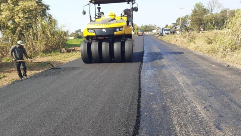 A imagem mostra homem e máquina trabalhando na compactação do novo asfalto