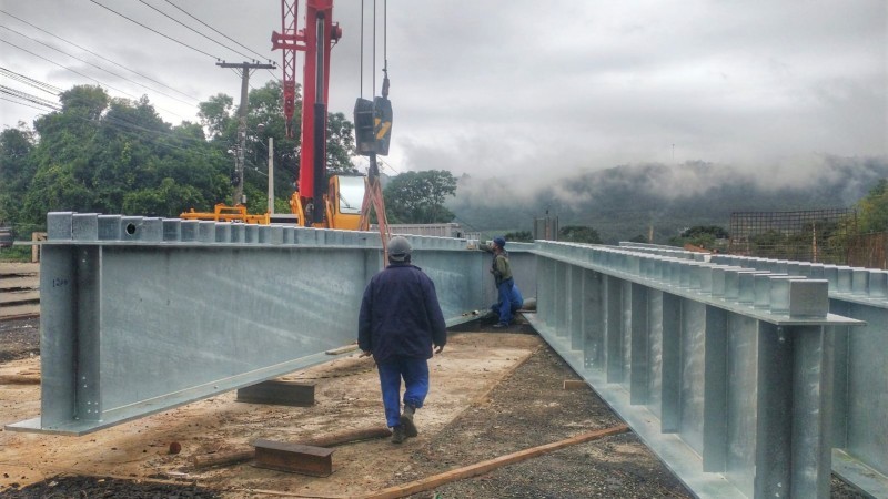 Trabalhador caminha entre duas vigas de concreto.