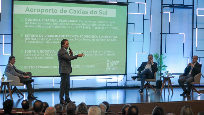 Na foto, o secretário é um homem branco, de terno, cabelos escuros, e fala ao microfone.
