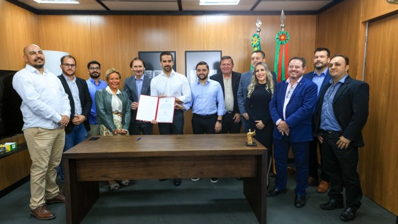 Na foto, o governador é um homem branco, cabelos escuros, usa camisa branca, cercado de integrantes do governo do Estado e prefeitos da Serra.