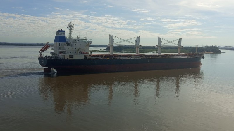 Na imagem há um grande navio de cargas navegando pelo Guaíba. 