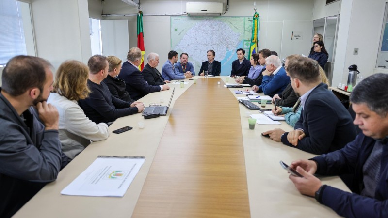 A imagem mostra uma sala de reuniões com o secretário de Logística e Transportes, Juvir Costella, e prefeitos do Vale do Taquari.