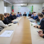 A imagem mostra uma sala de reuniões com o secretário de Logística e Transportes, Juvir Costella, e prefeitos do Vale do Taquari.