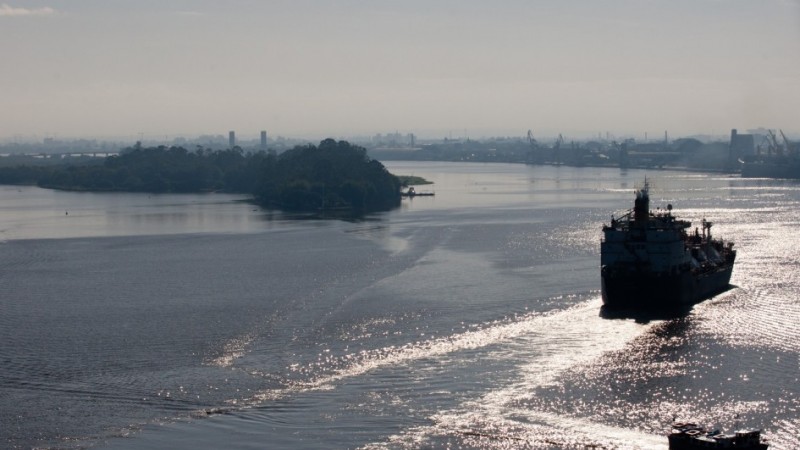 Na imagem, um barco navega pelo rio próximo a uma ilha.