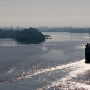 Na imagem, um barco navega pelo rio próximo a uma ilha.